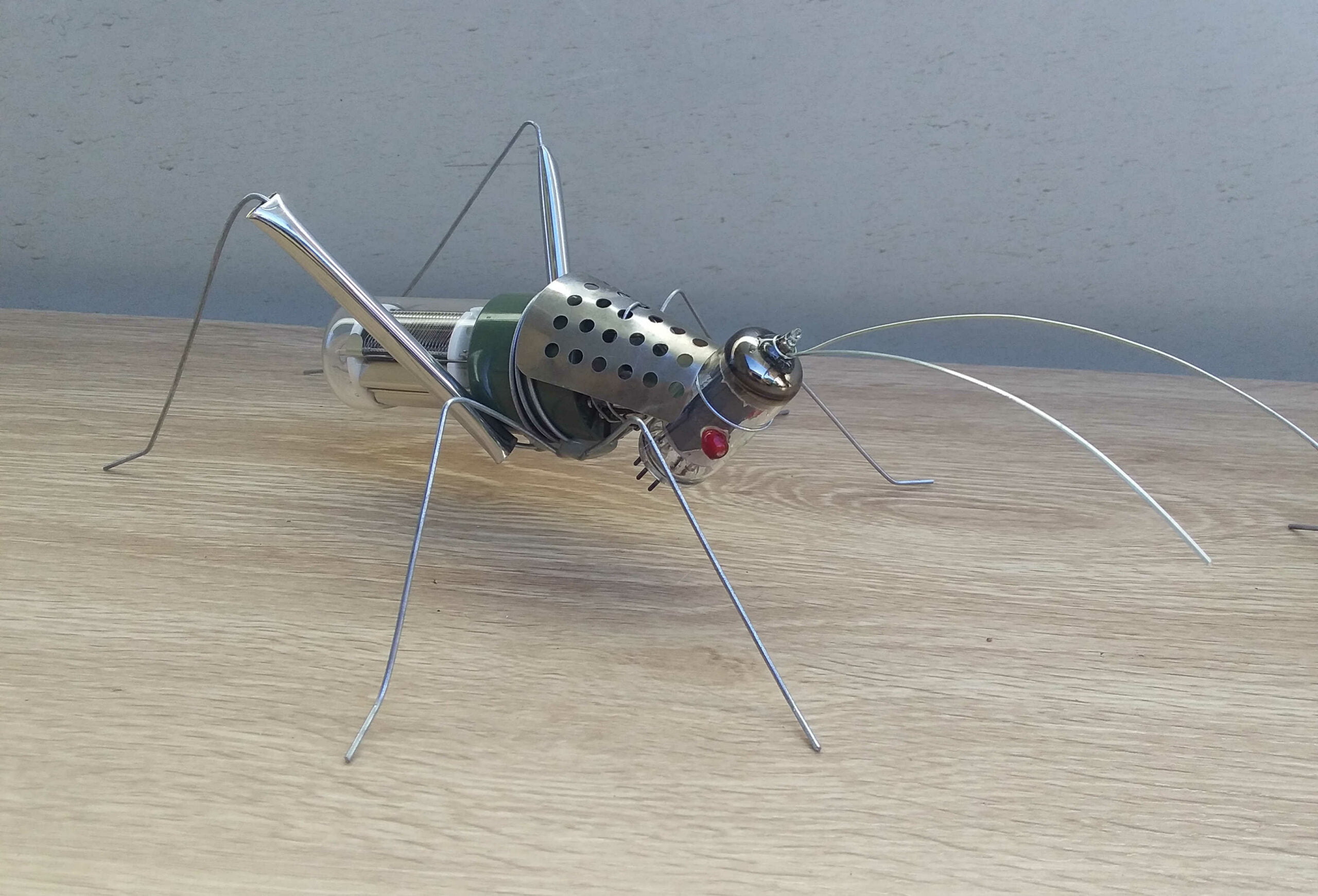 Grasshopper from 'Celebrating Diversity' by Libby Bloxham. It's constructed from recycled glass and electrical components, including tubular light bulbs for the body and head, radio antennae and wire.