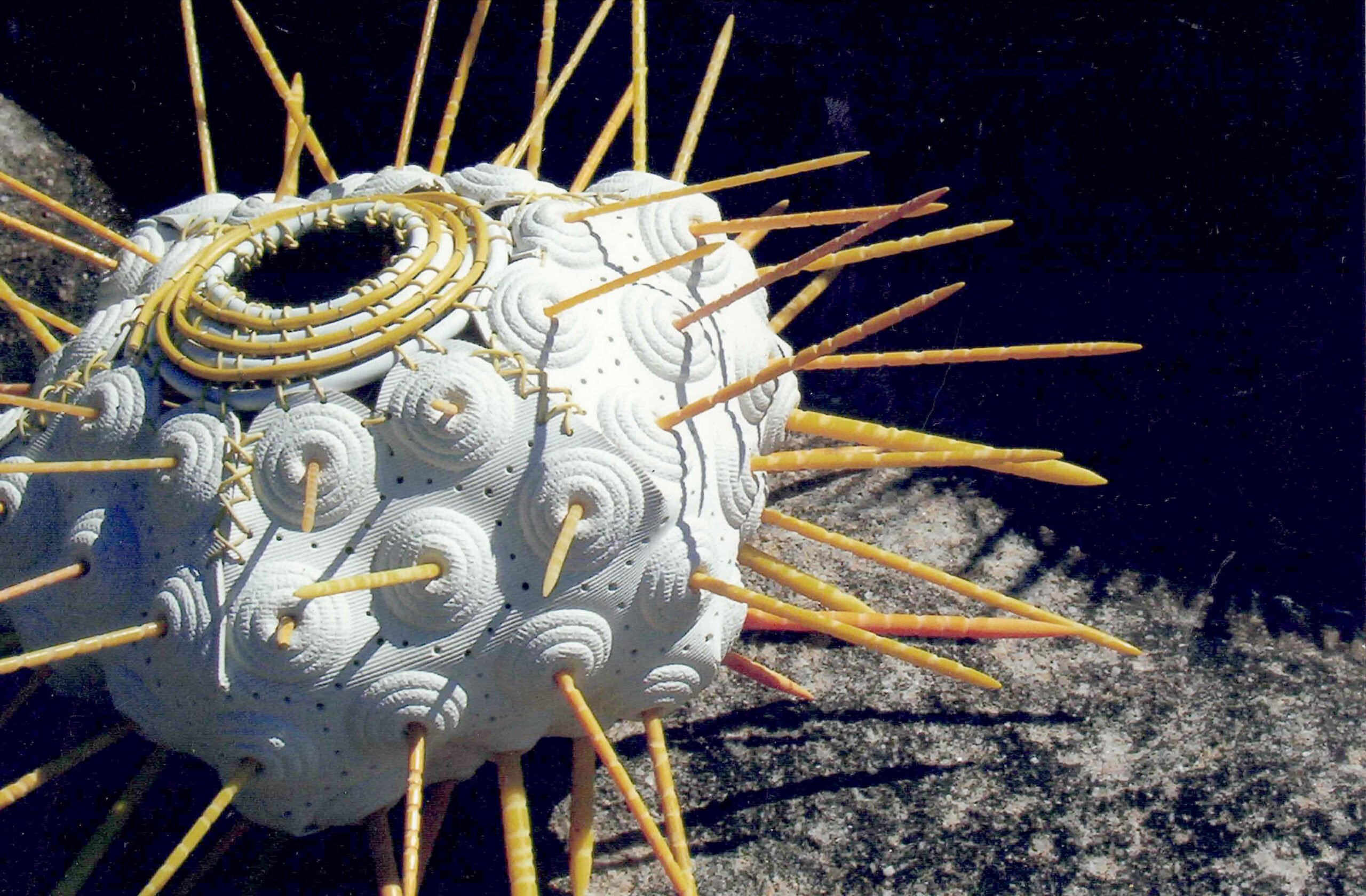 Sea Urchin from 'So Nice to be Beside the Seaside' by Libby Bloxham. This sculpture depicts a huge white sea urchin with bright yellow spikes,  assembled from found and repurposed objects including textured rubber bath mats and plastic knitting needles.